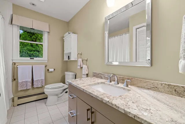 a bathroom with a granite countertop sink toilet and mirror