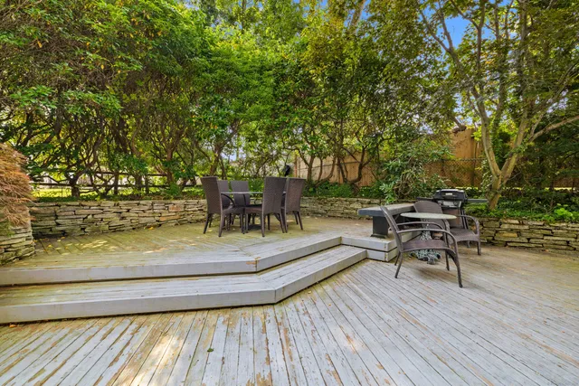 a view of a roof deck with table and chairs with wooden floor and fence