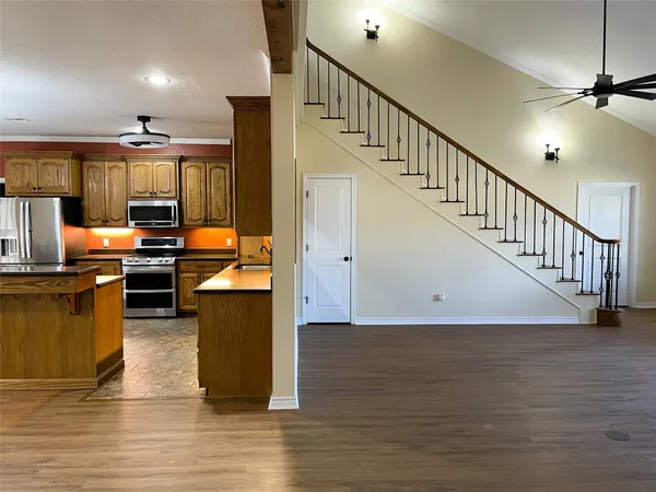 an empty room with wooden floor chandelier fan and windows