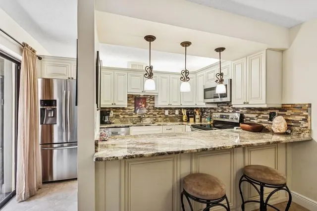 a kitchen with kitchen island granite countertop a table chairs stove refrigerator and cabinets