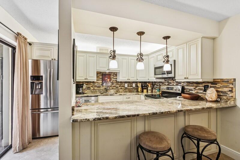 a kitchen with kitchen island granite countertop a table chairs stove refrigerator and cabinets