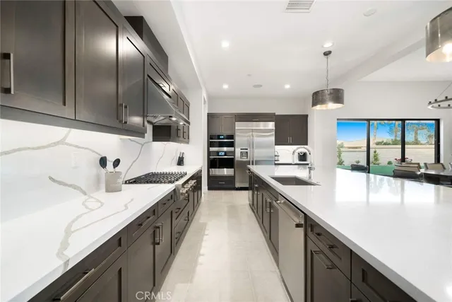 a kitchen with stainless steel appliances kitchen island granite countertop a sink a stove and a refrigerator
