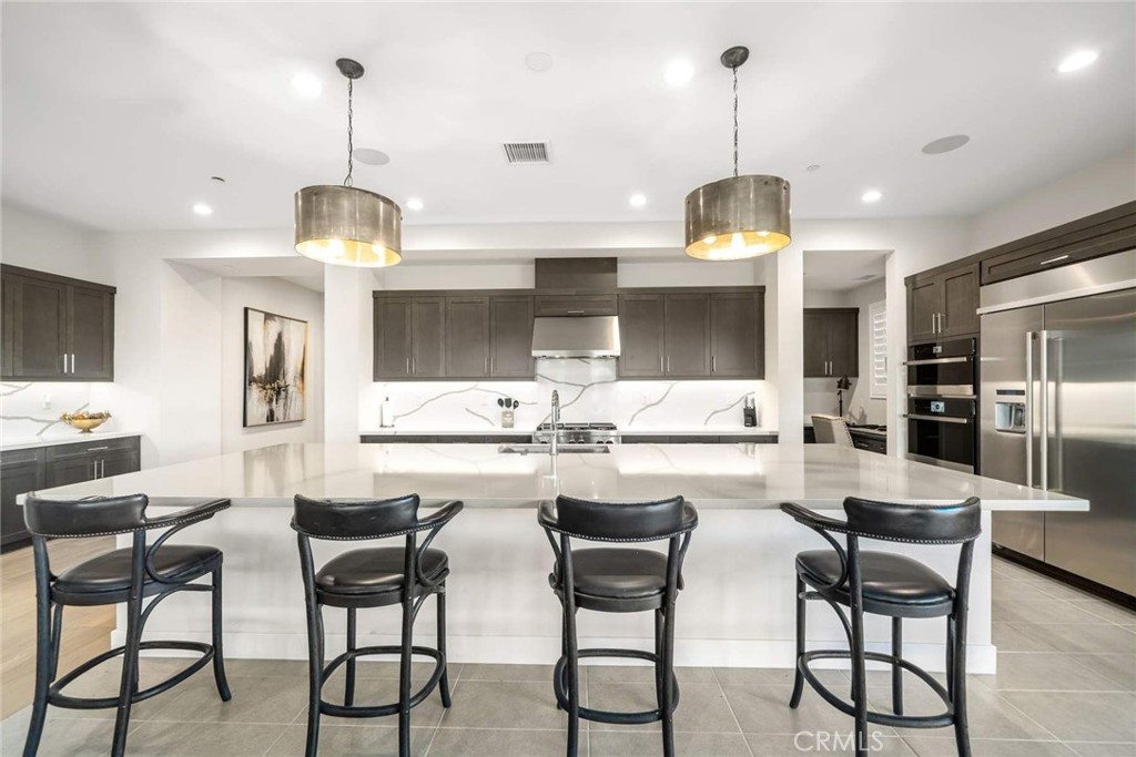 80495 Old Ranch Trail South La Quinta, CA 92253 - Photo 18 of 58 a kitchen with stainless steel appliances a dining table chairs and white cabinets