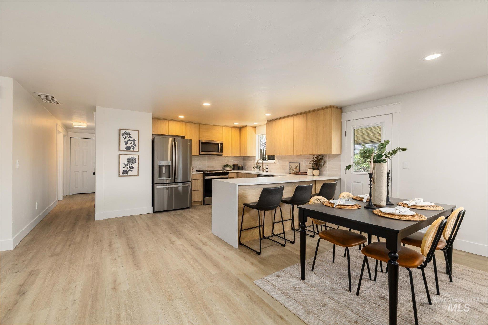 2220 Panama Street Boise, ID 83705 - Photo 13 of 27 Kitchen featuring a peninsula, stainless steel appliances, light wood finish cabinets, a breakfast bar area, and light wood finished floors