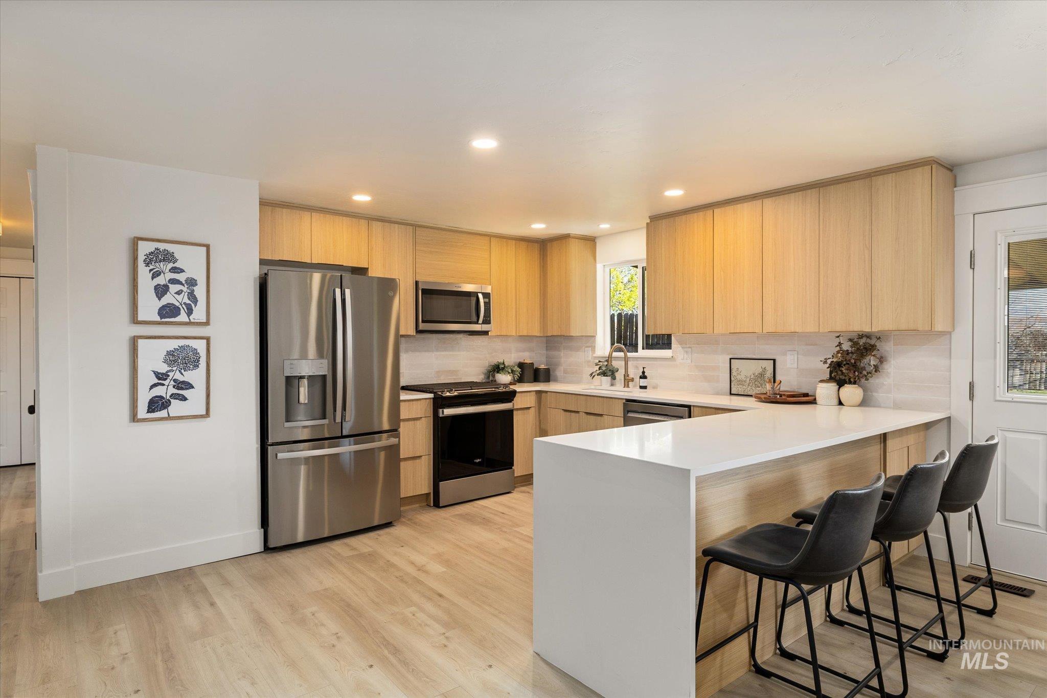 2220 Panama Street Boise, ID 83705 - Photo 9 of 27 Kitchen featuring stainless steel appliances, a peninsula, a breakfast bar, modern cabinets, and light wood finish cabinetry
