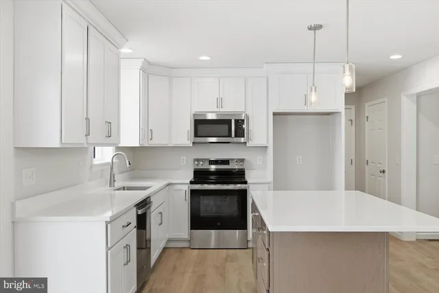 a kitchen with granite countertop white cabinets and stainless steel appliances