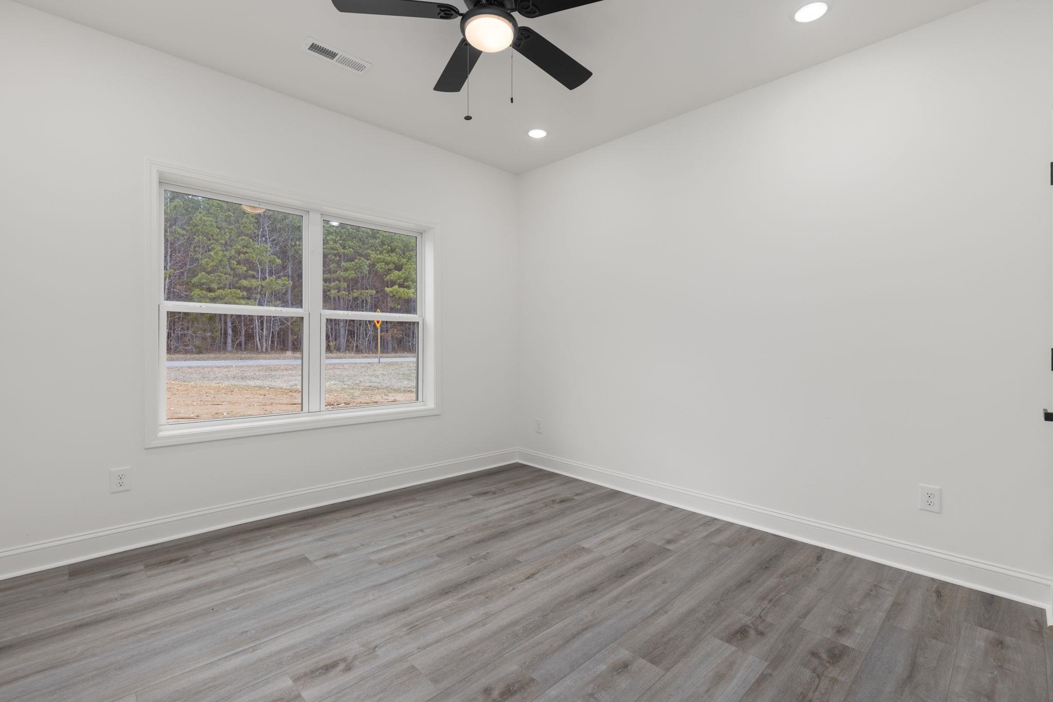 460 County Road 514 Rienzi, MS 38865 - Photo 15 of 29 an empty room with wooden floor chandelier fan and windows