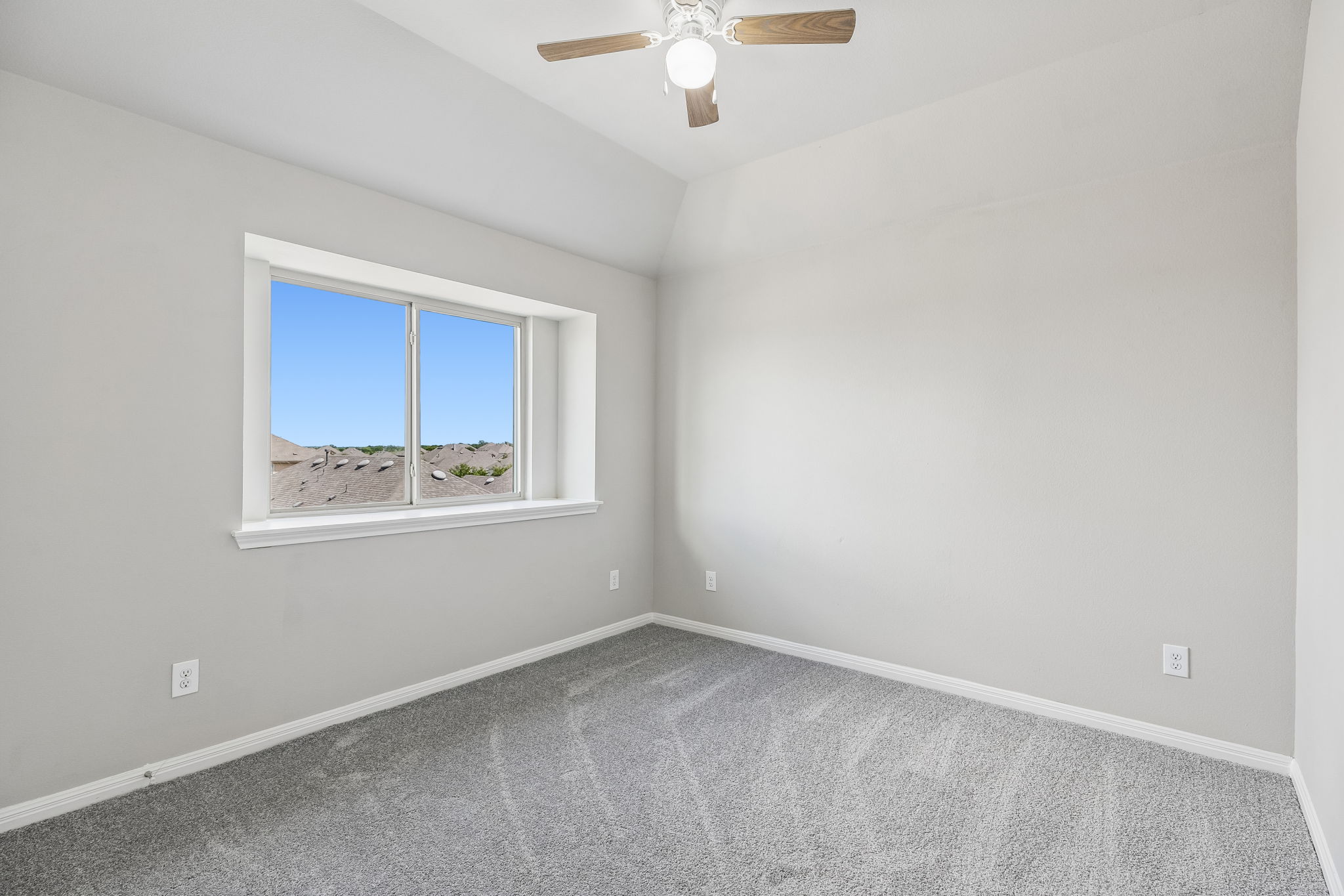 689 Nautical Loop Kyle, TX 78640 - Photo 25 of 34 A well-lit bedroom features vaulted ceilings and a window overlooking a distant landscape.