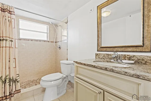 a bathroom with a granite countertop sink mirror vanity and toilet