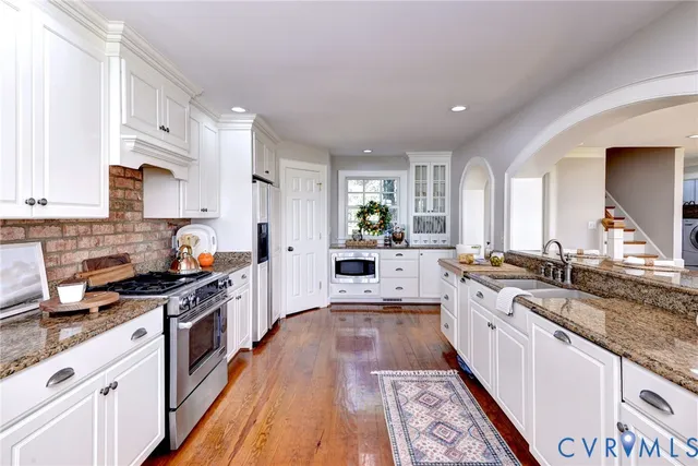 a large kitchen with stainless steel appliances granite countertop a lot of counter space and wooden floors