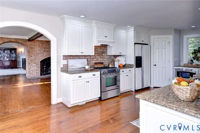 a kitchen with stainless steel appliances kitchen island granite countertop a stove a sink and white cabinets
