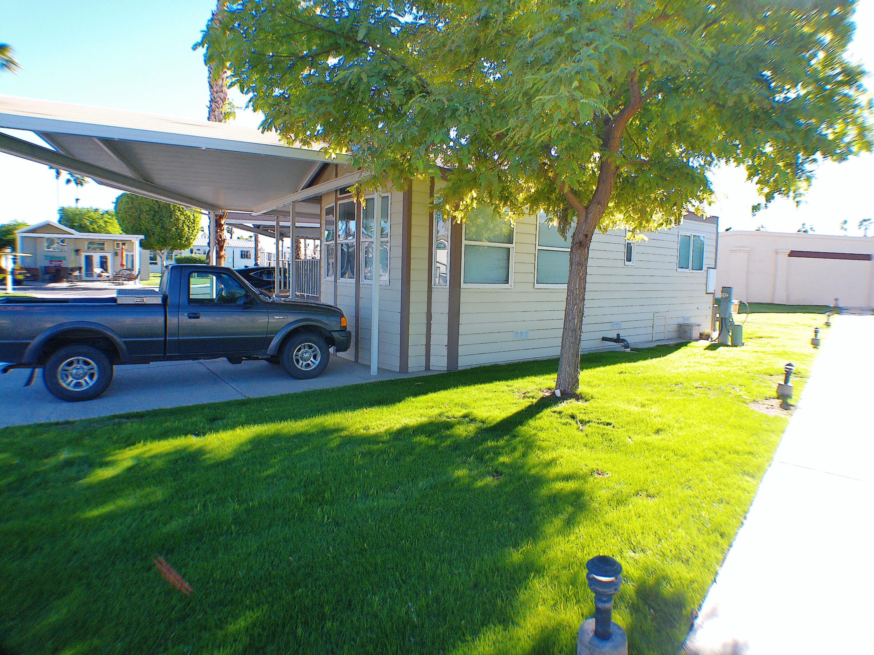 84136 Ave 44, Unit 477 Indio, CA 92203 - Photo 3 of 24 a view of a backyard with table and chairs under an umbrella