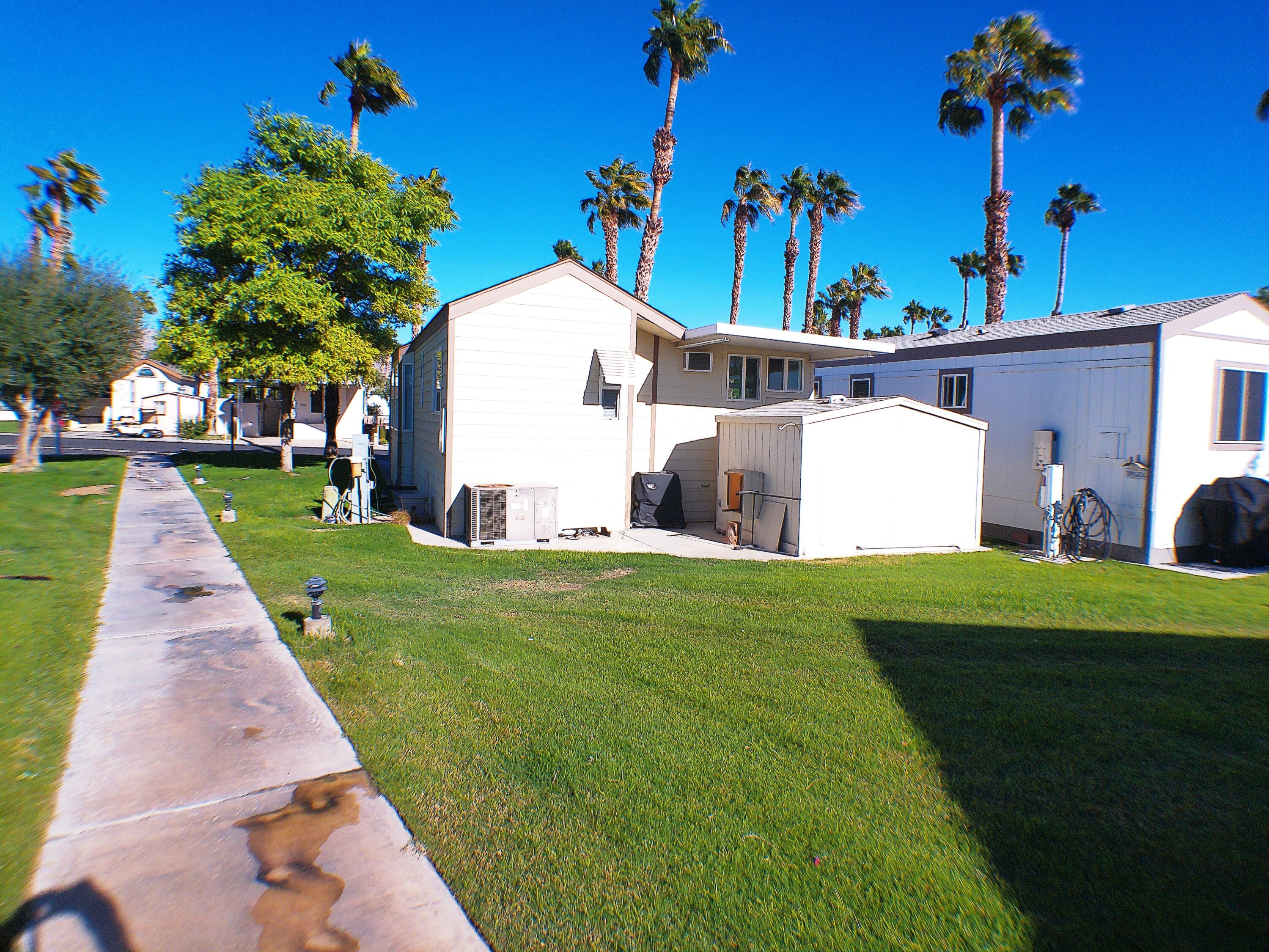 84136 Ave 44, Unit 477 Indio, CA 92203 - Photo 4 of 24 a view of a white house with a yard and potted plants