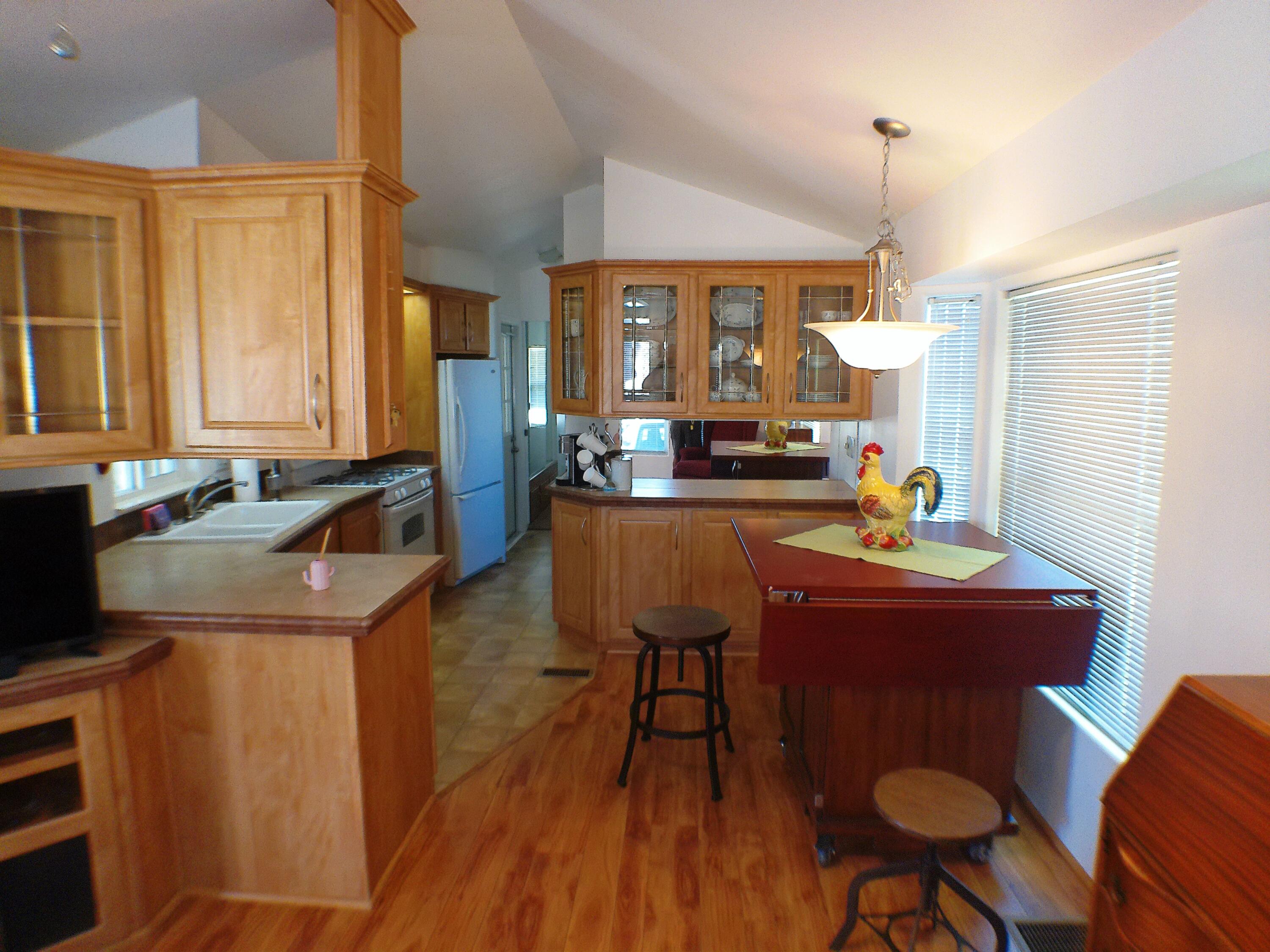 84136 Ave 44, Unit 477 Indio, CA 92203 - Photo 7 of 24 a kitchen with stainless steel appliances granite countertop a sink dishwasher a stove a dining table with chairs and wooden floor