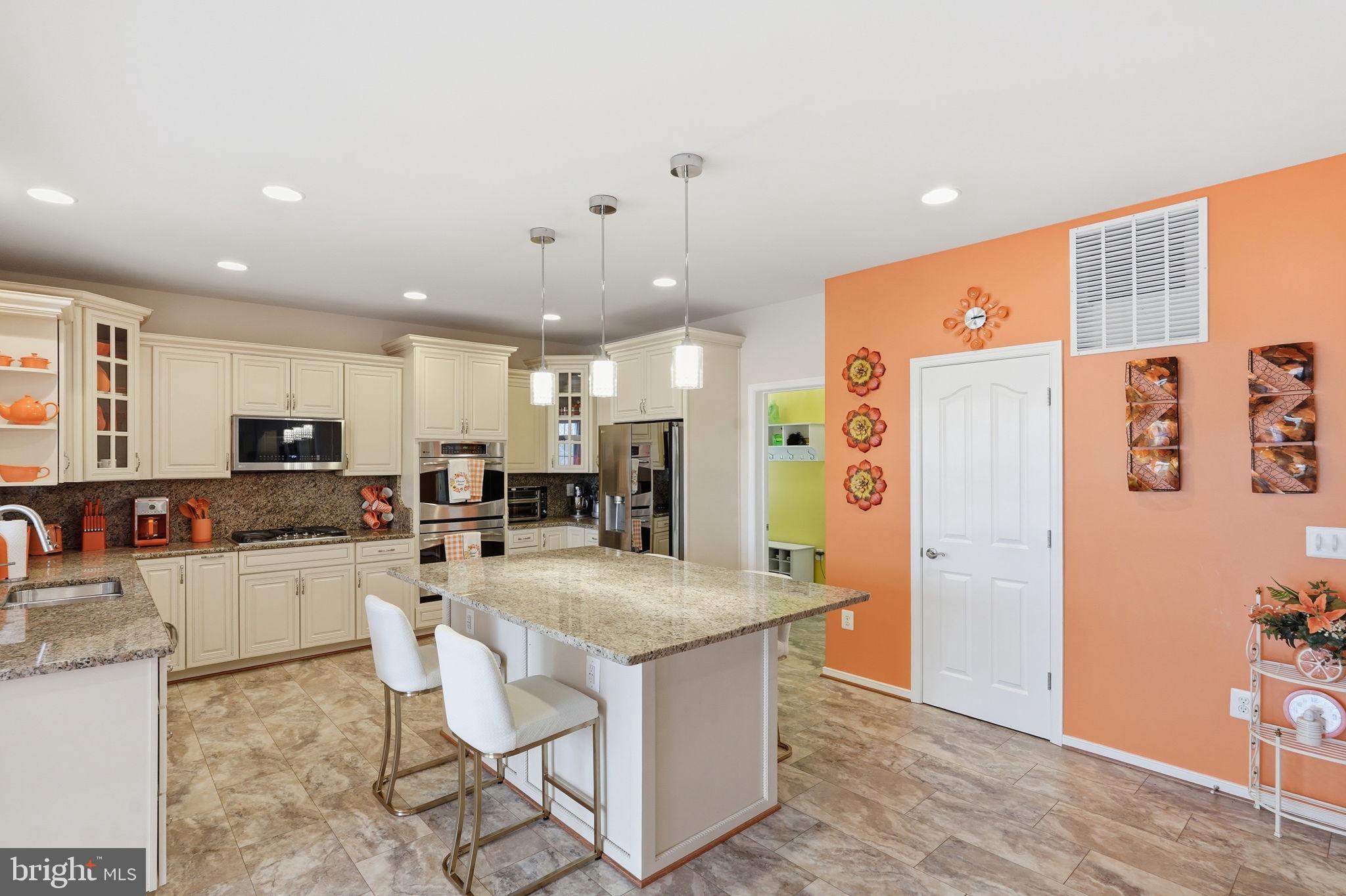 14 Smelters Trace Road Stafford, VA 22554 - Photo 12 of 78 a kitchen with stainless steel appliances kitchen island granite countertop a refrigerator a stove a sink a dining table and chairs with wooden floor