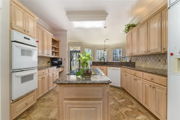 a kitchen with kitchen island granite countertop appliances cabinets and a counter space