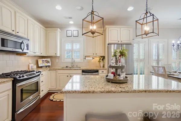 a kitchen with stainless steel appliances granite countertop a stove a refrigerator and a wooden floor