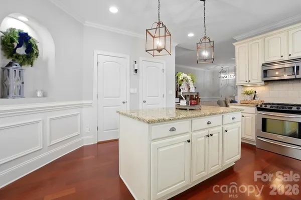 a kitchen that has a lot of white cabinets and stainless steel appliances
