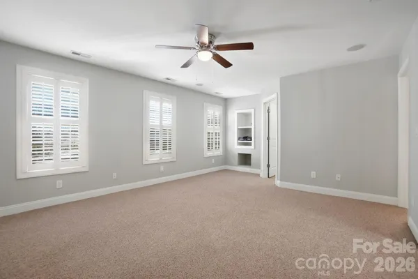 an empty room with a ceiling fan and window
