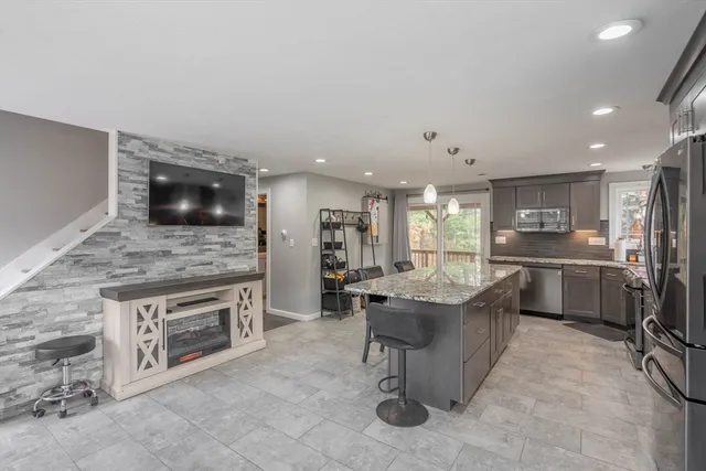 a living room with stainless steel appliances kitchen island granite countertop furniture a fireplace and a kitchen view