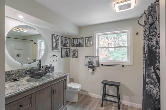 a bathroom with a granite countertop sink toilet and mirror