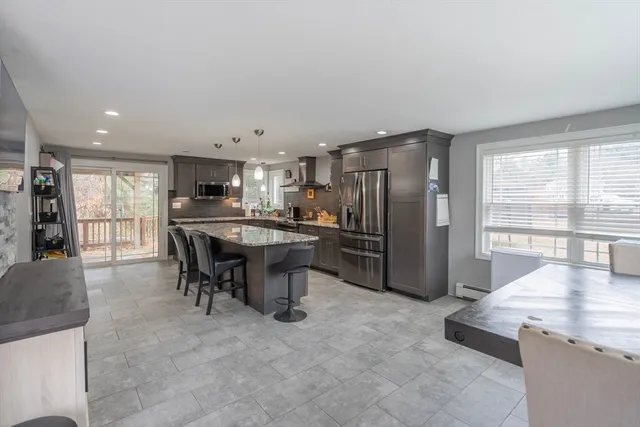 a kitchen with stainless steel appliances kitchen island granite countertop a refrigerator and a sink