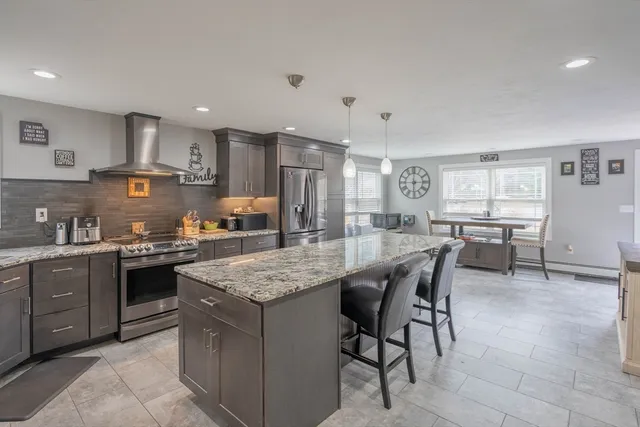 a kitchen with stainless steel appliances granite countertop table chairs sink and cabinets