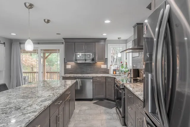 a kitchen with stainless steel appliances granite countertop a refrigerator a sink a stove and a wooden floors