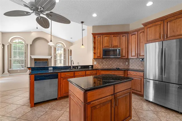 a kitchen with stainless steel appliances granite countertop a sink refrigerator and cabinets