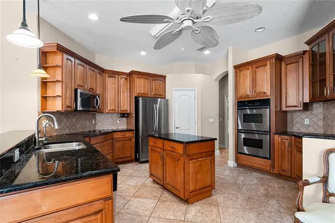 a kitchen with stainless steel appliances granite countertop a refrigerator oven a sink dishwasher and white cabinets with wooden floor