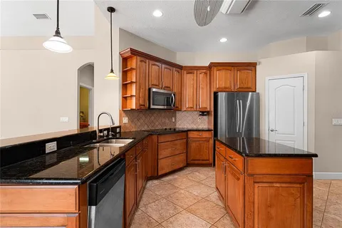 a kitchen with stainless steel appliances granite countertop a sink and a refrigerator