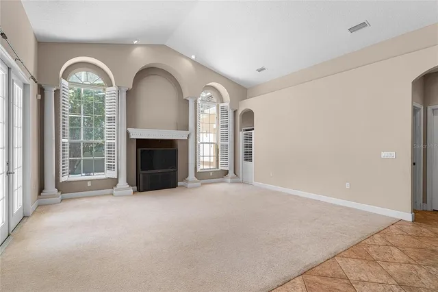 an empty room with windows fireplace and a dishwasher