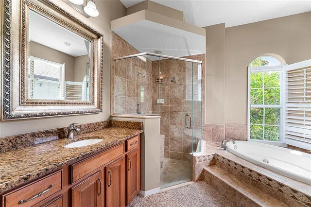 a bathroom with a granite countertop tub a sink and a large mirror