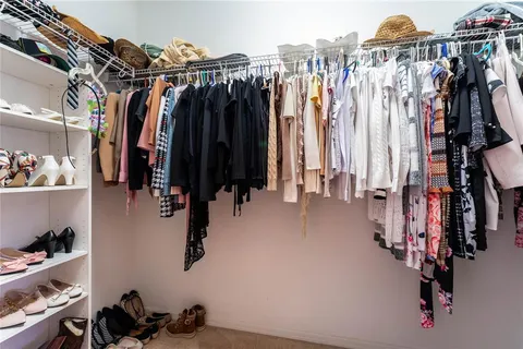 a view of walk in closet with clothes and shoes