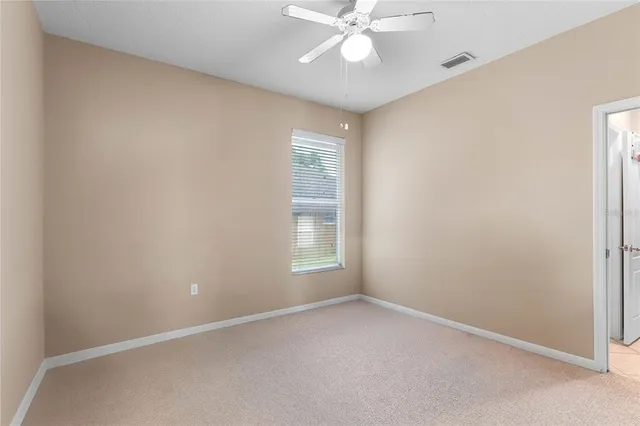 an empty room with a window and a fan