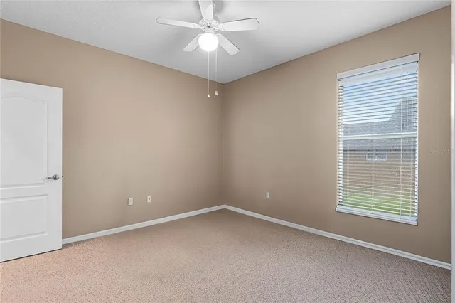 an empty room with a window and a fan