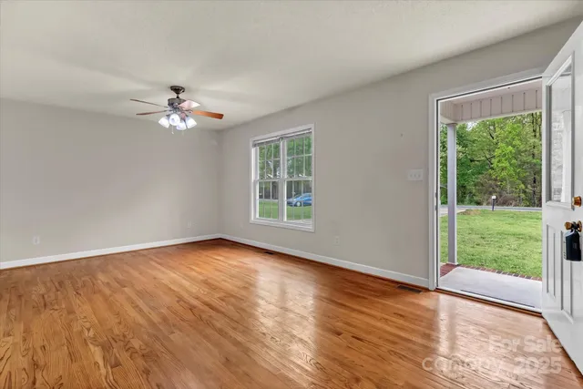 a view of an empty room with a window and wooden floor