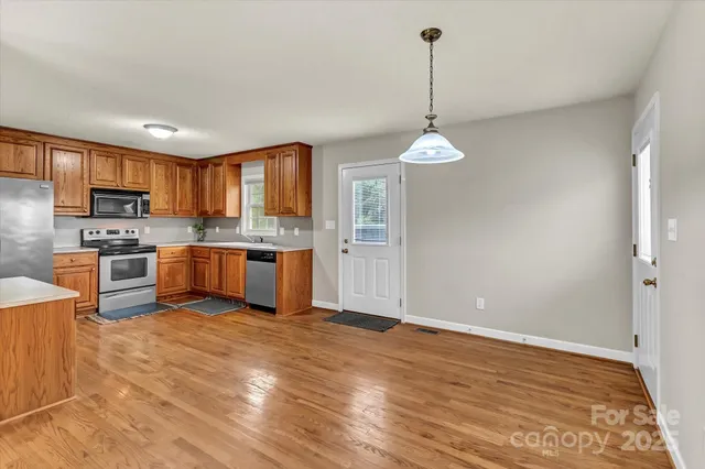 a kitchen with stainless steel appliances granite countertop a stove top oven a sink dishwasher and a refrigerator with wooden floor