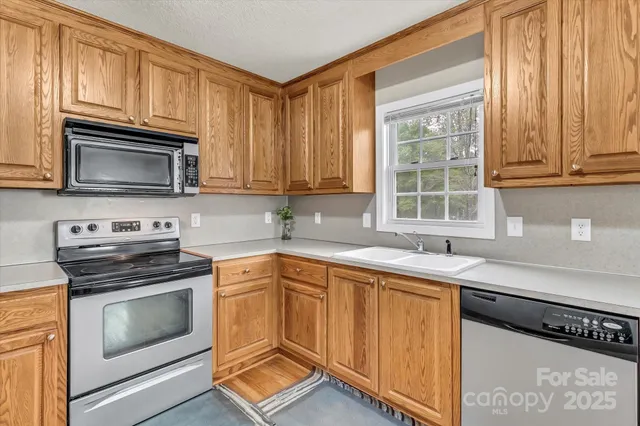 a kitchen with granite countertop a sink stainless steel appliances and cabinets