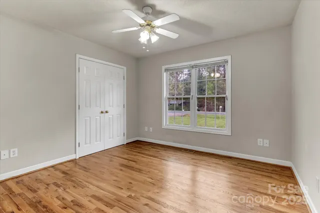 a view of empty room with wooden floor and fan