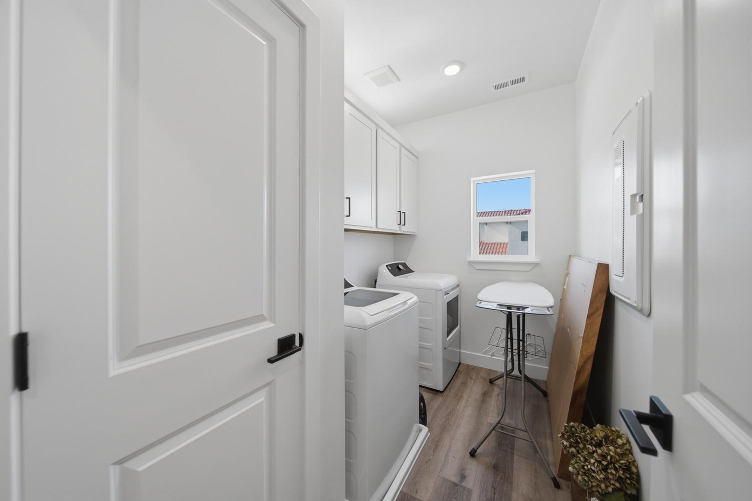 6144 Red Sand Lane St. George, UT 84790 - Photo 17 of 19 Function meets thoughtful design in the laundry room, complete with a full-size washer and dryer, upper cabinetry for extra storage, and a built-in ironing station tucked neatly to the side. A window brings in natural light, while durable flooring stands up to everyday household demands.