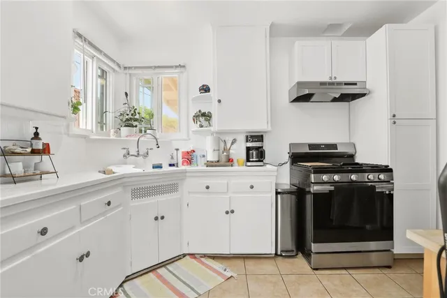 a kitchen that has a lot of cabinets a sink and a stove top oven