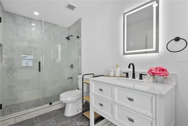 a bathroom with a granite countertop sink mirror toilet and shower