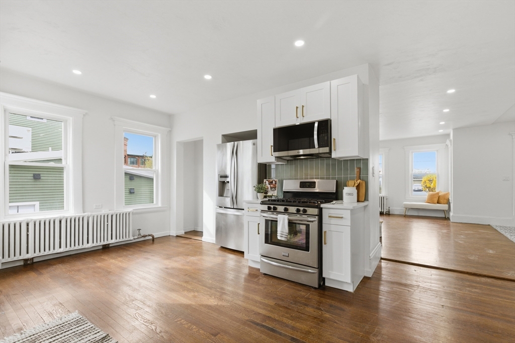 9 Robbins Street Waltham, MA 02453 - Photo 15 of 42 a kitchen with stainless steel appliances a stove top oven a sink a refrigerator white cabinets and wooden floor