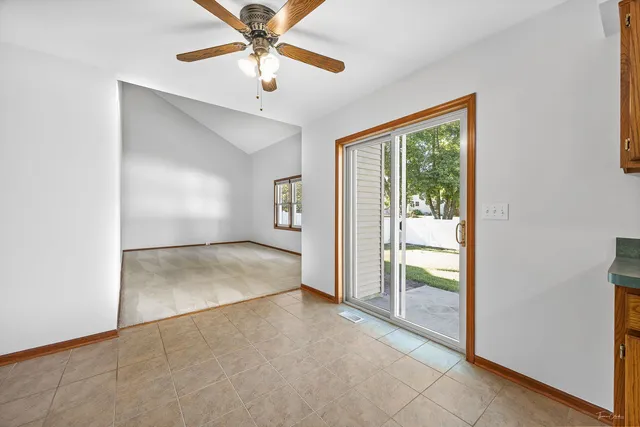 an empty room with chandelier fan and windows