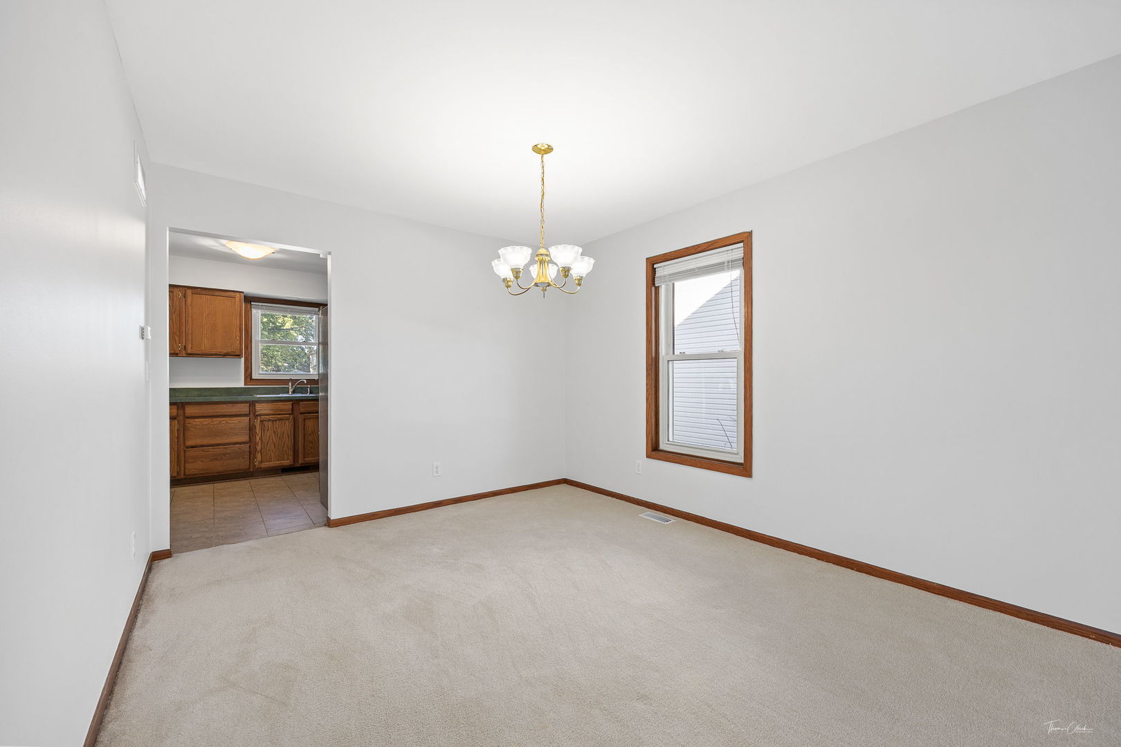 703 Avondale Lane Aurora, IL 60504 - Photo 6 of 40 an empty room with chandelier fan and kitchen view