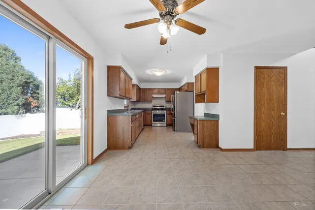 a open kitchen with stainless steel appliances kitchen island granite countertop a refrigerator a oven a sink with a dining table and chairs