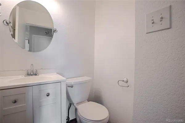a bathroom with a granite countertop toilet sink and mirror