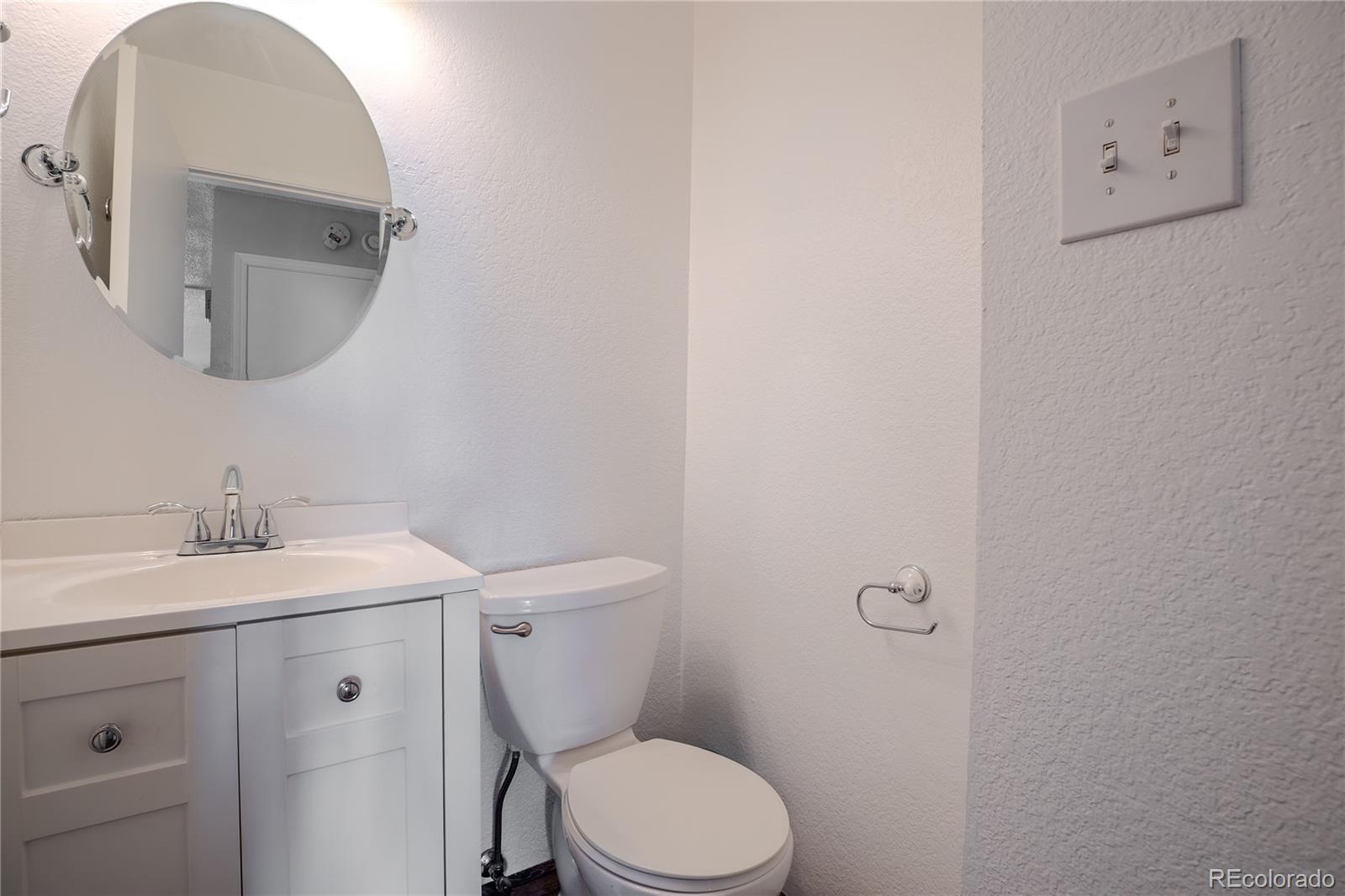 6315 Oak Street, Unit 2 Arvada, CO 80004 - Photo 11 of 34 a bathroom with a granite countertop toilet sink and mirror