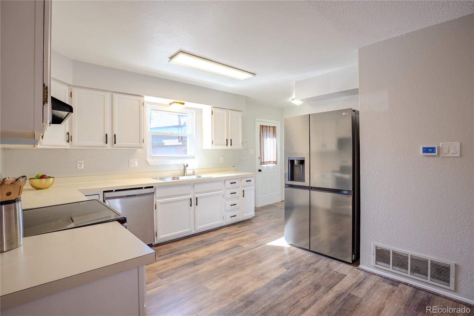 6315 Oak Street, Unit 2 Arvada, CO 80004 - Photo 26 of 34 a kitchen with a refrigerator a sink dishwasher and white cabinets with wooden floor